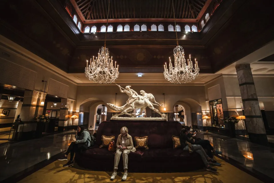 Grand hotel lobby with crystal chandeliers and a marble sculpture