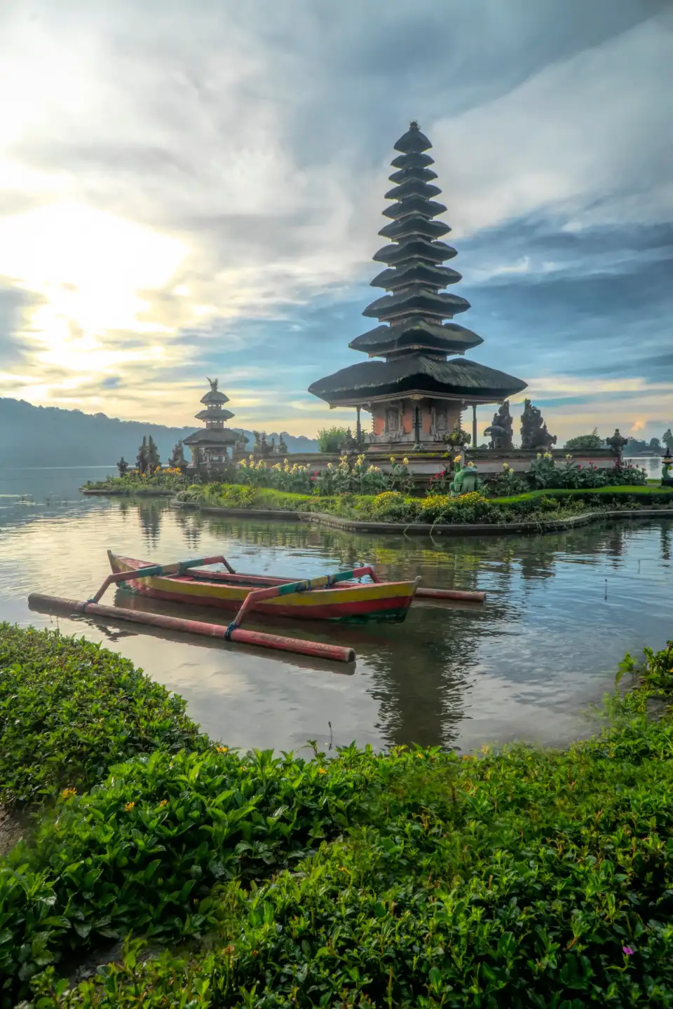 Ulun Danu Beratan temple on Lake Bratan with a traditional boat at dawn