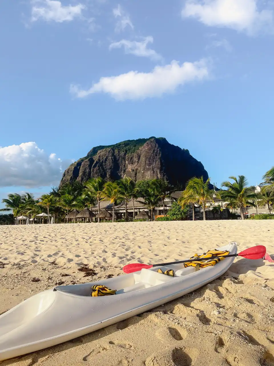 Kayak on a sandy beach with palm trees below Le Morne Brabant mountain