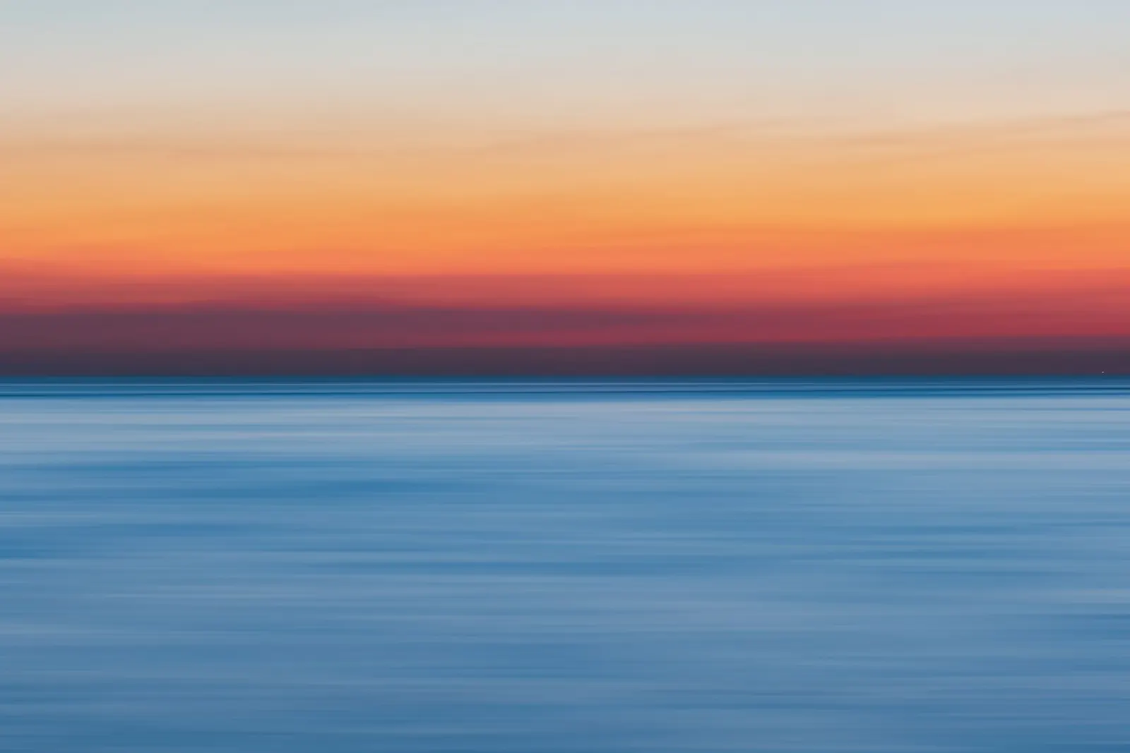 Calm sea meeting the horizon under a soft golden hour sky
