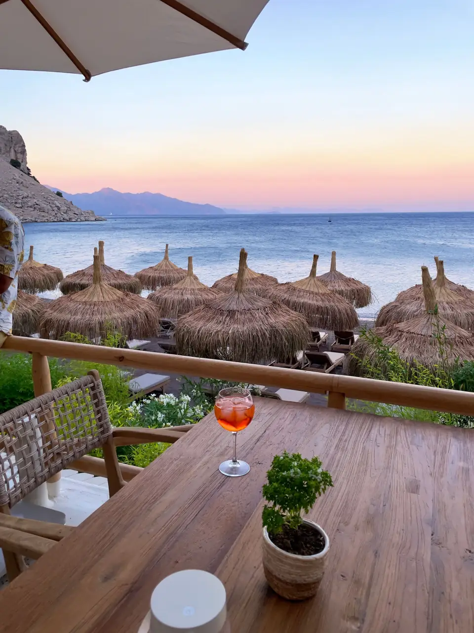 Wooden table with a drink on a beach restaurant terrace overlooking the sea
